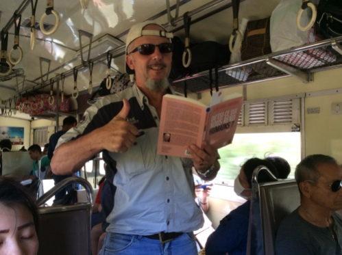 Dr Patrick Martiny reading the book on a train in Thailand